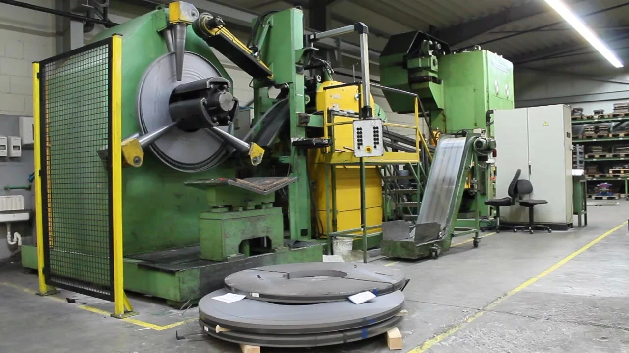 Coil-Abwickler vor einer Presse, davor liegende Stahlcoils