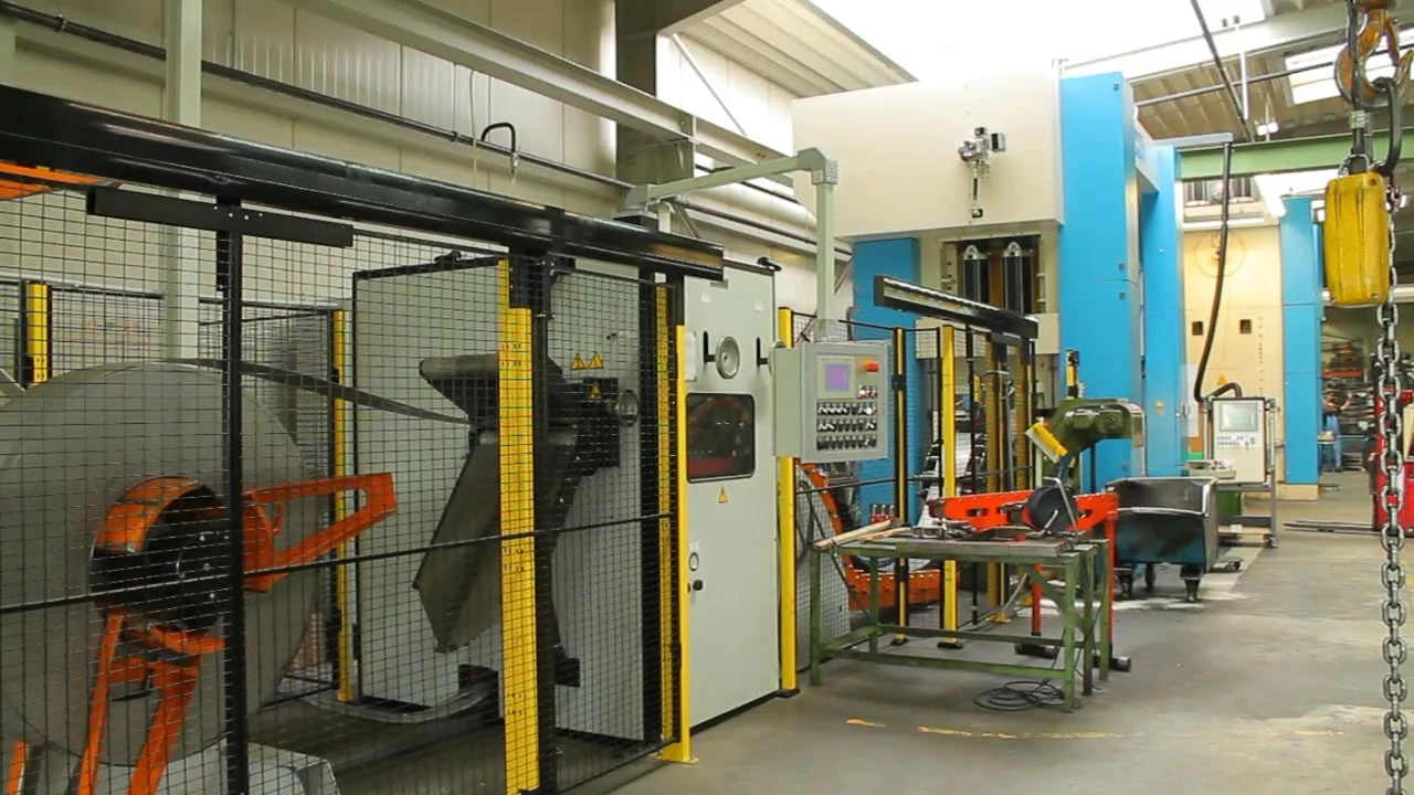 Coil-Abwickler und Bandzuführung vor einer Stanzpresse in der Halle der baco Metallwaren GmbH, Szene aus dem Imagefilm