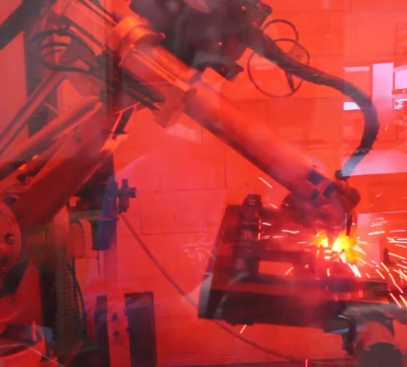 Schweißroboter bei der Arbeit hinter rotem Schutzglas